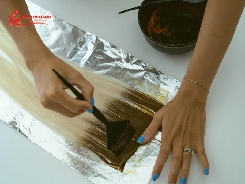 Applying lightener to hair extensions on foil.