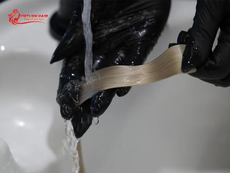 Rinsing lightened hair extensions to remove bleach residue.