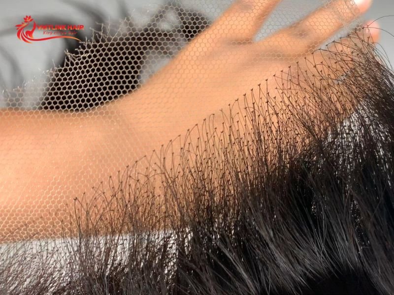 Close-up of hair knots and lace construction on a wig base.